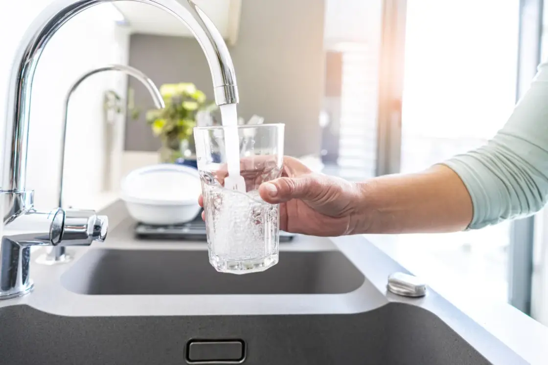 Close up woman hand filling a glass of water directly from the tap. Water contamination symptoms