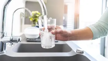 Close up woman hand filling a glass of water directly from the tap. Water contamination symptoms