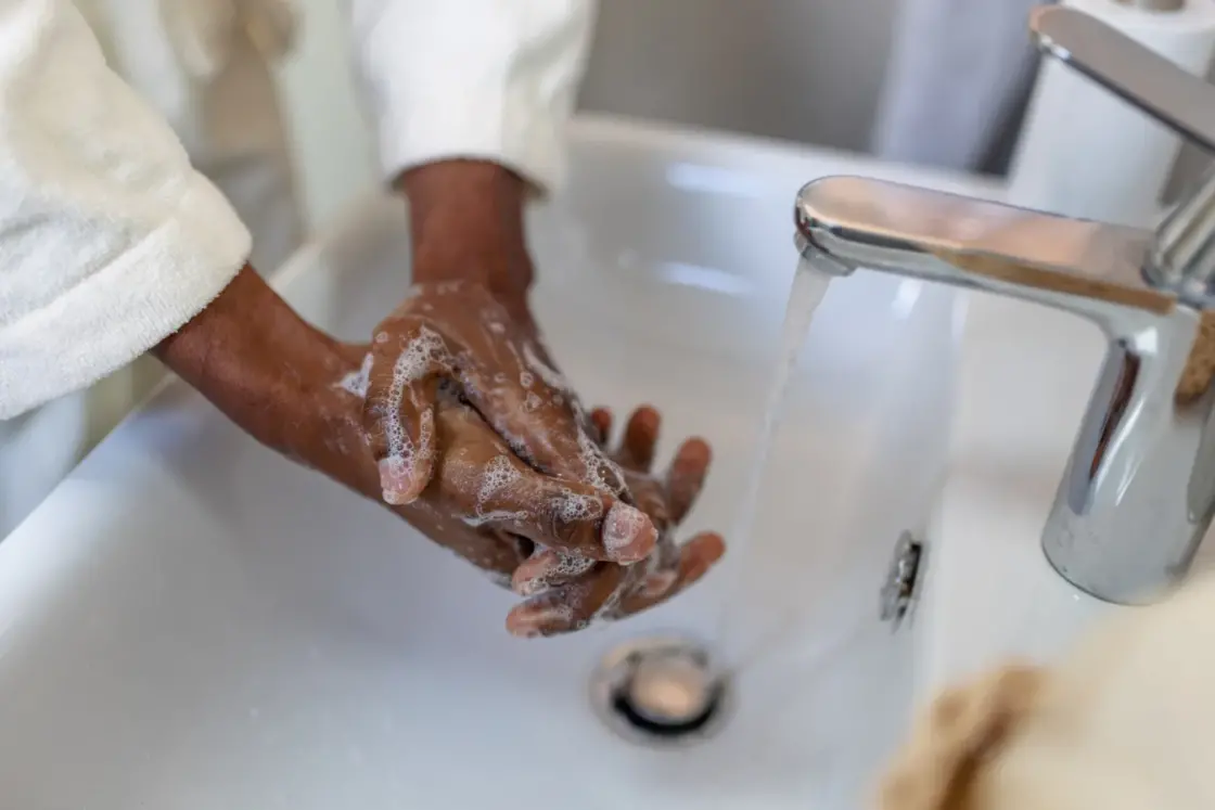 Close-up of a person lathering hands with soap and water over a bathroom sink, promoting soft water