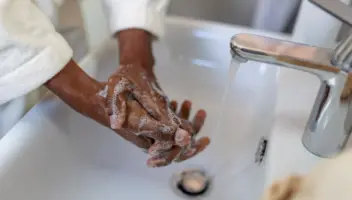 Close-up of a person lathering hands with soap and water over a bathroom sink, promoting soft water